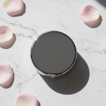 Silk Veil Pressed Powder Compact silver round compact closed, overhead flat lay on marble with rose petals