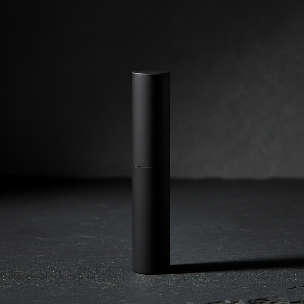Noir Bullet Lipstick matte black tube closed upright on dark grey slate surface