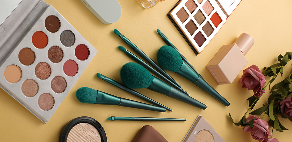 Makeup products including palettes, brushes, and flowers on a yellow background